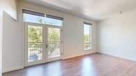 Located at 1710 R St in Sacramento's vibrant Midtown neighborhood, this well-designed one-bedroom, one-bathroom residence offers a thoughtful layout across a single floor. Warm hardwood-style flooring flows throughout the entire space, lending a clean and cohesive aesthetic.

The open-concept living area seamlessly integrates the living room, dining area, and kitchen into one bright, airy space. A set of glass-panel French doors opens to a private balcony, flanked by additional large windows that flood the interior with natural light and offer leafy outdoor views. The kitchen features white cabinetry, open shelving, a range with a hood vent, and a full-size refrigerator.

A welcoming hallway leads from the entrance toward the main living areas, with multiple closets providing generous storage throughout. The den offers flexible space that can serve as a home office or additional lounge area. The bedroom is a comfortable, light-filled retreat with its own window overlooking the tree-lined surroundings. The full bathroom is finished in a clean, modern style with a floating vanity, a tub-shower combination, and hardwood-style flooring. An in-unit laundry area adds everyday convenience, completing this efficiently designed urban residence.