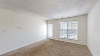 Located in North Charleston, South Carolina, this single-floor residence offers a practical and comfortable layout with two bedrooms and two bathrooms. The open living room is bright and welcoming, featuring plush wall-to-wall carpeting, neutral-toned walls, a textured ceiling, and large windows fitted with blinds that allow generous natural light while maintaining privacy. A door from the living room provides additional access to the outdoors.

The kitchen flows directly off the living area and is equipped with white cabinetry, a full suite of white appliances including a range, microwave, and refrigerator, as well as a double sink and wood-look flooring that adds warmth to the space.

Both bedrooms are carpeted and filled with natural light from well-positioned windows. The spacious primary bedroom includes access to a walk-in closet, while the second bedroom also features ample closet space. The two bathrooms are clean and functional; one includes a full tub/shower combo with chrome fixtures, while the other features wood-look flooring, a vanity with storage, and built-in cabinetry.

A dedicated laundry room with washer and dryer hookups, wire shelving overhead, and wood-look flooring adds everyday convenience to this well-organized residence.