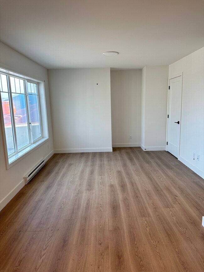 Bright and spacious lounge area overlooking beautifully landscaped yard with grass and flowers. - 3387 Ryder Hesjedal Way