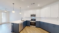 Located at 900 N Allen Ave in Richmond, VA, this well-designed apartment offers three bedrooms and three full bathrooms across a thoughtfully laid-out single floor. Light-toned hardwood-style flooring runs throughout the unit, lending a clean, cohesive look to every room. The kitchen is a standout feature, showcasing two-tone cabinetry with slate-blue lower cabinets and crisp white uppers, complemented by white quartz countertops, a subway tile backsplash, and a full suite of stainless steel appliances including a French door refrigerator, range, microwave, and dishwasher. Globe pendant lighting adds a modern finishing touch. The spacious primary bedroom benefits from multiple windows that invite natural light and offer views of the surrounding cityscape. Additional bedrooms are bright and neutrally finished, ready to be personalized. Each bathroom mirrors the kitchen's design language, featuring blue vanity cabinetry, white countertops, framed mirrors, and neutral tile flooring. The primary bath includes a dual-sink vanity for added convenience. A private balcony, dedicated closet, and connecting hallway round out this functional and stylish urban residence.