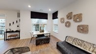 This contemporary single-floor residence in Bethlehem, PA offers a thoughtfully designed open-concept layout with modern finishes throughout. The kitchen is a standout feature, equipped with stainless steel appliances including a gas range, built-in microwave, and refrigerator, complemented by rich dark cabinetry, white quartz countertops, and a classic subway tile backsplash. A sliding glass door connects the kitchen directly to a private outdoor balcony, filling the space with natural light and exterior views. The combined living and dining area is bright and versatile, with large windows dressed in sleek black Roman shades, light hardwood-style flooring, and a textured accent wall that adds visual depth. The primary bedroom is a sophisticated retreat featuring bold deep green accent panels flanking the headboard wall, plush carpeting, and ample natural light from a large window. A walk-in closet with built-in shelving provides generous storage. The primary bathroom offers a long vanity with a white countertop, dark wood cabinetry, subway tile shower with glass enclosure, and hardwood-style flooring. A second bathroom mirrors the same refined aesthetic. The overall ambiance is clean, modern, and cohesive, with consistent use of dark wood tones, white surfaces, and contemporary fixtures throughout.