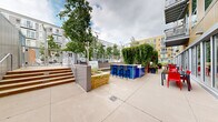 Located at 101 10th St E in Saint Paul, Minnesota, this thoughtfully designed outdoor courtyard serves as a dynamic communal gathering space nestled between several multi-story residential buildings. The grounds are richly landscaped with a diverse mix of perennial gardens, ornamental grasses, mature shade trees, and flowering plants — including vibrant black-eyed Susans, coneflowers, and hostas — that provide seasonal color and texture throughout.

Winding concrete and gravel pathways meander through the greenery, connecting distinct zones within the courtyard. A central entertainment area features a bold blue outdoor bar with bar-height seating, ideal for social gatherings. Adjacent raised stone planters with built-in greenery and comfortable lounge seating offer a relaxed setting beneath the tree canopy. Steps lead up to what appears to be a pool or water feature area, adding another layer of amenity to the space.

A lush ivy-covered living wall provides a dramatic green backdrop near the bar area, while low-profile bollard lighting lines the pathways for evening use. A dome-shaped shelter tucked into the garden offers a quiet retreat. The overall ambiance is one of an urban green oasis — well-maintained, layered with plant life, and designed to encourage both active use and peaceful relaxation amidst the surrounding cityscape.