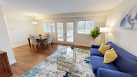 This well-appointed single-floor residence offers a thoughtfully designed layout that balances comfort and functionality. The open-concept living and dining area serves as the heart of the home, bathed in natural light streaming through multiple windows and a set of glass doors that provide direct outdoor access and views of surrounding greenery. Warm hardwood flooring flows seamlessly throughout the space, complementing the soft, neutral wall tones that lend a bright and welcoming ambiance.

The kitchen is outfitted with crisp white shaker-style cabinetry extending to the ceiling for ample storage, white tile backsplash, light countertops, and a full suite of stainless steel appliances including a refrigerator, dishwasher, microwave, and range — combining a clean aesthetic with practical functionality.

The two bedrooms are comfortably sized, each featuring hardwood floors, large windows that invite natural light, and generous closet space. One bedroom includes a spacious walk-in closet with a clothing rod and skylight, while the second features a sliding-door closet for convenient storage.

The bathroom is neatly appointed with a pedestal sink, a shower-tub combination, and a large mirror, maintaining the home's clean and understated design palette. Throughout the residence, consistent finishes and an abundance of natural light create a cohesive, inviting atmosphere.