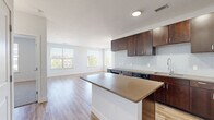 Located at 250 Summit Blvd in Broomfield, Colorado, this well-appointed two-bedroom, one-bathroom residence offers a thoughtfully designed single-floor layout. The open-concept kitchen and living area serves as the heart of the home, featuring rich dark-stained cabinetry, a light glass tile backsplash, stainless steel appliances, and a center island with quartz-tone countertops — all set atop warm wood-look flooring that extends throughout the main living spaces. The kitchen flows seamlessly into a bright, airy living room illuminated by multiple large windows and a glass door that opens to a private balcony, offering views of the surrounding neighborhood and mature trees.

Both bedrooms are carpeted for comfort and include ceiling fans, generous windows for natural light, and dedicated closets outfitted with wire shelving systems for organized storage. The primary bedroom is particularly spacious, providing ample room for a full furniture arrangement. The bathroom is finished with wood-tone cabinetry, quartz-style countertops, wood-look flooring, and a full tub-shower combination with classic white subway tile surround and brushed nickel fixtures. Clean white walls and consistent finishes throughout lend the space a cohesive, modern aesthetic.