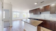 Located at 250 Summit Blvd in Broomfield, Colorado, this well-appointed two-bedroom, one-bathroom residence offers a thoughtfully designed single-floor layout. The open-concept kitchen and living area serves as the heart of the home, featuring rich dark-stained cabinetry, a light glass tile backsplash, stainless steel appliances, and a center island with quartz-tone countertops — all set atop warm wood-look flooring that extends throughout the main living spaces. The kitchen flows seamlessly into a bright, airy living room illuminated by multiple large windows and a glass door that opens to a private balcony, offering views of the surrounding neighborhood and mature trees.

Both bedrooms are carpeted for comfort and include ceiling fans, generous windows for natural light, and dedicated closets outfitted with wire shelving systems for organized storage. The primary bedroom is particularly spacious, providing ample room for a full furniture arrangement. The bathroom is finished with wood-tone cabinetry, quartz-style countertops, wood-look flooring, and a full tub-shower combination with classic white subway tile surround and brushed nickel fixtures. Clean white walls and consistent finishes throughout lend the space a cohesive, modern aesthetic.