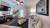 This single-story residence offers a thoughtfully designed layout that balances comfort and functionality across its key living spaces. The open-concept living room features dark hardwood-style flooring, crown molding, and a ceiling fan, creating a welcoming atmosphere complemented by a door that allows natural light to filter in. The space flows naturally into a dedicated dining area, where crown molding continues and a pendant light fixture anchors the room above a dining table set.

The kitchen is outfitted with white shaker cabinetry, granite countertops, and a full suite of stainless steel appliances, including an electric range with over-the-range microwave and a refrigerator. The clean, bright aesthetic makes it both practical and visually appealing.

Two bedrooms provide comfortable accommodations; one features hardwood-style flooring and the other plush carpet, each offering ample space for furnishings. The bathroom maintains the home's consistent design language with a white vanity, granite countertop, and hardwood-style flooring.

A dedicated laundry room houses a full-size washer and dryer, complemented by wire shelving for additional storage. Throughout the home, neutral wall tones, white baseboards, and cohesive finishes create a clean, unified aesthetic.
