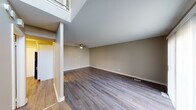 Located at 3318 83rd St in Woodridge, Illinois, this two-story home offers a thoughtfully designed layout with distinct living spaces spread across both levels. The main living area immediately impresses with its soaring double-height ceiling, which floods the space with a sense of openness and volume. A ceiling fan adds functionality, while durable hardwood-style flooring runs throughout the main level, lending a clean, contemporary feel.

The kitchen is well-appointed with white cabinetry, dark granite countertops, a stainless steel sink, and matching stainless steel appliances, including a refrigerator and dishwasher. A sliding glass door in the adjacent living area opens to a balcony, allowing natural light to pour in and providing a connection to the outdoors.

A half bathroom on the main level features wood-style flooring, a white vanity, and a corner-mounted toilet. Upstairs, the bedrooms are carpeted for comfort, with neutral walls and ample natural light from windows. The primary bedroom stands out with generous dual closet space featuring built-in shelving and hanging rods. The full upper bathroom includes a white vanity, a framed mirror, and a tub-shower combination with tiled surround.