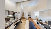 Located at 525 NW 77th St in Boca Raton, FL, this two-bedroom, three-bathroom two-story residence offers a thoughtfully designed layout across two floors. The main level immediately impresses with dramatic double-height ceilings in the living area, creating a grand sense of openness and airiness. Light wood flooring flows seamlessly throughout, complementing the clean, neutral palette of the walls.

The open-concept living and dining area provides an inviting gathering space, with the living room anchored by vaulted ceilings and natural light streaming through windows. A light wood staircase connects the two floors and serves as an architectural focal point. The kitchen features rich dark cabinetry, granite-style countertops, stainless steel appliances, and ample storage, opening directly to the dining area for easy entertaining.

A bedroom on the main level offers convenient single-floor living. The primary bedroom, located upstairs, is a generously sized retreat with windows that bring in natural light, a dedicated workspace nook, and direct access to a sitting area. The three bathrooms are clean and functional, each featuring tub-shower combinations with white tile surrounds and light wood-look flooring. The overall ambiance is modern, bright, and welcoming throughout.