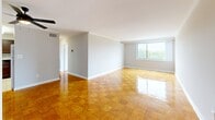 This single-floor, 2-bedroom, 1-bathroom home offers a practical and comfortable layout across a generous footprint. Distinctive warm-toned parquet wood flooring flows throughout the living areas and bedrooms, lending a classic character to the space. The open living area is bright and airy, accented by crown molding and a ceiling fan with light fixture, creating a welcoming atmosphere. Large windows frame sweeping views of the surrounding greenery and cityscape, filling the home with abundant natural light.

The kitchen is well-equipped with rich brown cabinetry, dark granite countertops, tile flooring, and a peninsula breakfast bar that opens to the living area — ideal for casual dining and entertaining. Crown molding adds a refined touch to the kitchen as well.

The primary bedroom is generously sized, featuring large windows with scenic outdoor views and a full-width mirrored sliding closet that enhances the sense of space. The second bedroom also features parquet flooring, mirrored closet doors, and its own window. The bathroom is clean and functional, featuring a tiled tub-shower combination. A hallway connects the rooms, completing this efficient and thoughtfully arranged home.