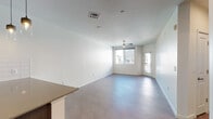 This contemporary single-floor residence offers a clean, modern aesthetic throughout, with a thoughtfully designed layout that balances open communal areas with comfortable private spaces. The living area is bright and airy, featuring large windows that invite natural light, light-toned tile flooring, a ceiling fan, and direct access to an exterior door — creating a welcoming and functional space. Adjacent to the living area, the kitchen is well-appointed with dark wood cabinetry, a full suite of stainless steel appliances including a French door refrigerator, range, over-the-range microwave, and dishwasher, complemented by a white subway tile backsplash and stone-finish countertops. The two bedrooms are generously proportioned, each outfitted with ceiling fans and windows that bring in natural light. One bedroom features soft wall-to-wall carpeting, while the other offers the same plush comfort with an exterior-facing window. The full bathroom is finished with large-format wall tiles in a warm taupe tone surrounding the tub-shower combination, paired with a dark vanity, stone-topped counters, a wide mirror, and brushed nickel fixtures — delivering a refined, spa-like feel. Crisp white walls and consistent finishes throughout lend the space a cohesive and modern character.