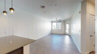 This contemporary single-floor residence offers a clean, modern aesthetic throughout, with a thoughtfully designed layout that balances open communal areas with comfortable private spaces. The living area is bright and airy, featuring large windows that invite natural light, light-toned tile flooring, a ceiling fan, and direct access to an exterior door — creating a welcoming and functional space. Adjacent to the living area, the kitchen is well-appointed with dark wood cabinetry, a full suite of stainless steel appliances including a French door refrigerator, range, over-the-range microwave, and dishwasher, complemented by a white subway tile backsplash and stone-finish countertops. The two bedrooms are generously proportioned, each outfitted with ceiling fans and windows that bring in natural light. One bedroom features soft wall-to-wall carpeting, while the other offers the same plush comfort with an exterior-facing window. The full bathroom is finished with large-format wall tiles in a warm taupe tone surrounding the tub-shower combination, paired with a dark vanity, stone-topped counters, a wide mirror, and brushed nickel fixtures — delivering a refined, spa-like feel. Crisp white walls and consistent finishes throughout lend the space a cohesive and modern character.