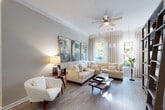 This thoughtfully designed single-floor residence offers a seamless blend of comfort and style across its well-appointed rooms. The expansive living area serves as the heart of the home, featuring wide-plank hardwood flooring, crown molding, and a ceiling fan overhead. Large windows dressed with flowing neutral drapes allow abundant natural light to pour in, offering views of lush greenery outside. A generous sectional sofa in cream anchors the space, complemented by a triptych of abstract artwork in muted greens and whites that adds a sophisticated artistic touch.

The kitchen is efficiently laid out with light maple cabinetry, granite countertops, a classic subway tile backsplash with under-cabinet lighting, and a stainless steel sink — providing both practicality and clean aesthetic appeal.

The primary bedroom is a tranquil retreat, highlighted by a striking wrought-iron four-poster canopy bed, plush carpeting, and multiple windows that bathe the room in natural light. Rich wood dressers and nature-inspired wall art complete the refined atmosphere.

The dining area near the entry features wainscoting, crown molding, and a round table with tufted upholstered chairs, creating an intimate setting. The full bathroom is finished with dark granite countertops, white cabinetry, wood-look flooring, and a soaking tub-shower combination.