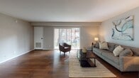 This single-floor residence offers a thoughtfully designed layout that balances comfort and functionality throughout. The living area serves as the heart of the home, featuring rich hardwood flooring, neutral warm-gray walls, and an abundance of natural light streaming in through large sliding glass doors that open directly to a private outdoor patio — ideal for seamless indoor-outdoor living.

The kitchen is a standout space, outfitted with crisp white cabinetry accented by dark hardware, dark granite countertops, and stainless steel appliances including a range and refrigerator. A marble-look tile floor adds a touch of elegance, while the galley-style layout maximizes efficiency and workspace.

The bedrooms are calm and inviting, each finished with hardwood flooring and neutral tones. Windows offer views of lush greenery, allowing natural light to fill the rooms and creating a serene atmosphere well-suited for rest.

The bathroom is cleanly finished with large-format earthy tile flooring, soft gray walls, white cabinetry, and a shower with a curtain enclosure, presenting a practical and cohesive design.

Throughout the space, consistent use of neutral tones, hardwood floors, and natural light creates a cohesive and welcoming ambiance that is both modern and livable.