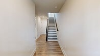 Located at 3101 Runnel Ln in Laurel, MD, this contemporary three-floor townhouse offers a well-designed layout across three distinct levels. The ground floor features a spacious garage with drywall-finished walls, multiple interior access doors, and ample storage potential. A clean hallway with light hardwood-style flooring and a striking staircase with dark treads and black metal railings connects the levels seamlessly.

The main living floor is the heart of the home, showcasing an open-concept kitchen and living area bathed in natural light from large windows. The kitchen is outfitted with crisp white shaker cabinetry, gold-toned hardware, stainless steel appliances, a tile backsplash, and a central island with a quartz countertop and undermount sink, illuminated by pendant lighting. The adjacent living area features light hardwood-style flooring and a glass door leading to an outdoor space.

The upper floor hosts three bedrooms, each with hardwood-style floors, neutral tones, and windows that invite natural light and outdoor views. The primary bedroom offers a generous footprint, while secondary bedrooms provide comfortable, functional spaces. The two bathrooms are finished with tile flooring, a glass-enclosed shower, white vanity cabinetry, and brushed gold fixtures, delivering a clean, modern aesthetic throughout.