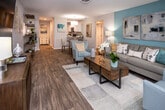 Located at 3399 Lake Brook Blvd in Knoxville, Tennessee, this single-floor residence offers a thoughtfully designed open-concept layout that seamlessly connects the living, dining, and kitchen areas. The living room is a standout space, anchored by a bold teal accent wall adorned with contemporary artwork, wood-look flooring, and a sliding glass door that invites natural light and outdoor views. The kitchen features crisp white cabinetry, granite-look countertops, stainless steel appliances including a range, microwave, and refrigerator, complemented by a skylight that brightens the space. A dedicated dining area with pendant lighting sits adjacent to the kitchen, creating a cohesive entertaining zone. The primary bedroom continues the teal accent wall theme, offering plush carpeting, a spacious dresser, and decorative wall art. Additional bedrooms provide comfortable retreats, each with carpeted floors, natural light from well-positioned windows, closet access, and calming sage-toned accent walls. The bathroom includes a full tub-shower combination with clean, neutral finishes. Throughout the residence, a consistent coastal-inspired color palette of teal, soft gray, and warm wood tones creates a cohesive and welcoming ambiance.