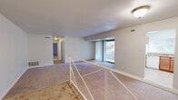 This single-floor residence offers a well-organized layout designed for comfortable everyday living. The living room serves as the central gathering space, finished with wall-to-wall carpeting and anchored by a large sliding glass door fitted with vertical blinds that opens to a balcony overlooking mature trees, allowing generous natural light to fill the room. A railed transition area connects the main living space to the rest of the unit, adding a subtle architectural detail to the floor plan.

The kitchen is equipped with warm-toned wood cabinetry, granite-style countertops, and white appliances including a refrigerator and dishwasher. A window above the sink provides natural light and outdoor views, enhancing the functionality of the space.

The bedrooms are carpeted and generously proportioned. One bedroom features an expansive wall of built-in closets with bifold doors, while another includes a walk-in closet and a window with views of surrounding greenery. Both rooms offer a quiet, neutral atmosphere.

The bathrooms are finished with clean, light tones. One features a wide vanity with white cabinetry and a large mirror, while the other includes a full tub and shower combination with white tile surround. Marble-style flooring adds a refined touch to the bathroom areas.