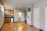 Located on the third floor at 4029 Rainier Ave S in Seattle's Rainier Beach neighborhood, this efficiently designed studio offers a smart, open-concept layout that combines the living, dining, and kitchen areas into one cohesive space. Warm-toned hardwood-style flooring runs throughout, complementing the neutral gray walls and white trim to create a clean, modern aesthetic. Recessed lighting keeps the interior bright and well-lit.

The kitchen is outfitted with wood-toned cabinetry, a dark countertop, an under-counter refrigerator, a sink, and a built-in microwave — providing all essential cooking amenities in a compact footprint. The living area benefits from multiple windows fitted with blinds, including a large window and a pair of upper clerestory windows that draw in natural light while maintaining privacy.

A dedicated alcove houses a stacked washer and dryer unit, offering the convenience of in-unit laundry. Two closets provide practical storage solutions. The bathroom, accessible via a sliding barn-style door, features a wall-mounted sink, a medicine cabinet with mirror, a toilet, a curtained shower, and grab bars for accessibility. The entryway is marked by a solid dark door, giving the unit a defined and secure entry point.