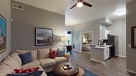 Located in Phoenix, AZ, this single-floor residence offers a well-designed layout that balances comfort and functionality. The open-concept living room features soaring ceilings, wood-look plank flooring, and a ceiling fan, creating a bright and airy atmosphere. A spacious sectional seating area is complemented by wall-mounted art and a wall-mount TV setup, making it ideal for relaxing or entertaining.

The kitchen is efficiently arranged with white cabinetry accented by black hardware, stainless steel appliances including a refrigerator, range, and microwave, and clean white countertops. It opens seamlessly toward the living and dining areas, promoting an connected flow throughout the main living space.

The dining area accommodates a round glass-top table beneath a statement pendant light, with vertical blinds covering a sliding glass door that leads to an outdoor area.

The bedroom is a serene retreat with elevated ceilings, a ceiling fan, plush carpeting, and a walk-in closet. Natural light filters through a large window dressed with vertical blinds. A second room with carpet and a sliding closet offers flexible use as an additional bedroom or office.

The bathroom features a wide vanity with white cabinetry, black hardware, a large mirror, and a tub-shower combination, all finished in a clean, bright palette with wood-look flooring for a cohesive aesthetic.