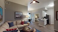 Located in Phoenix, AZ, this single-floor residence offers a well-designed layout that balances comfort and functionality. The open-concept living room features soaring ceilings, wood-look plank flooring, and a ceiling fan, creating a bright and airy atmosphere. A spacious sectional seating area is complemented by wall-mounted art and a wall-mount TV setup, making it ideal for relaxing or entertaining.

The kitchen is efficiently arranged with white cabinetry accented by black hardware, stainless steel appliances including a refrigerator, range, and microwave, and clean white countertops. It opens seamlessly toward the living and dining areas, promoting an connected flow throughout the main living space.

The dining area accommodates a round glass-top table beneath a statement pendant light, with vertical blinds covering a sliding glass door that leads to an outdoor area.

The bedroom is a serene retreat with elevated ceilings, a ceiling fan, plush carpeting, and a walk-in closet. Natural light filters through a large window dressed with vertical blinds. A second room with carpet and a sliding closet offers flexible use as an additional bedroom or office.

The bathroom features a wide vanity with white cabinetry, black hardware, a large mirror, and a tub-shower combination, all finished in a clean, bright palette with wood-look flooring for a cohesive aesthetic.