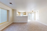 Located at 7929 W Mansfield Pkwy in Lakewood, Colorado, this single-floor, two-bedroom, two-bathroom unit offers a functional and straightforward layout. The open-concept living and kitchen area serves as the heart of the space, where a peninsula counter with a built-in sink visually connects the kitchen to the living room. The kitchen features wood-toned cabinetry with white cabinet fronts, a light-toned countertop, white appliances including a range, microwave, and refrigerator, and hardwood-style flooring. The living area extends comfortably beyond the peninsula, finished with neutral carpet and illuminated by a large multi-pane window and a glass patio door that invites natural light. Both bedrooms are carpeted and feature large windows that bring in views of surrounding greenery. The primary bedroom includes a built-in closet. The two bathrooms each feature wood-toned vanity cabinetry, light countertops, hardwood-style flooring, and a tiled tub-shower combination with neutral taupe tile. Throughout, the unit maintains a consistent neutral color palette of warm beige tones, creating a cohesive and understated ambiance.