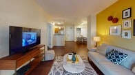 This single-floor residence at 44 Station Landing in Medford, MA features a thoughtfully designed open layout with rich hardwood flooring connecting the main living areas. The living room is anchored by a bold yellow accent wall, large windows admitting generous natural light, and ample space for comfortable seating arrangements. It flows seamlessly toward a dedicated dining area and into a well-equipped kitchen outfitted with warm honey-toned cabinetry, dark granite countertops, stainless steel appliances including a range, microwave, and refrigerator, and recessed lighting overhead.

The residence includes multiple bedrooms, each distinguished by its own accent wall—deep plum, navy blue, and warm mauve tones—paired with hardwood floors and windows with views to the exterior. Closet space is present in each room. Two full bathrooms feature tub-shower combinations, wood vanities with granite countertops, tile flooring, and backlit mirrors that lend a clean, contemporary feel. The overall design balances modern finishes with warm, residential touches, creating a cohesive and inviting atmosphere throughout the home.