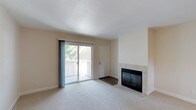 This single-floor residence offers a thoughtfully designed layout with a comfortable, neutral palette throughout. The spacious living room serves as the heart of the home, anchored by a classic tile-surround fireplace with black glass doors — an inviting focal point for relaxing or entertaining. A sliding glass door opens to an outdoor balcony, filling the room with natural light and providing views of the surrounding greenery. Light-toned carpet extends throughout the living areas and bedrooms, contributing to a warm and cohesive feel.

The kitchen is well-equipped with crisp white cabinetry, granite-style countertops, stainless steel appliances including a refrigerator, electric range, built-in microwave, and dishwasher, all set on durable wood-look flooring. The layout is efficient and functional, with ample counter and storage space.

The bedrooms are generously proportioned, each featuring plush carpet and large windows that frame views of mature trees and lush outdoor vegetation, lending a serene, nature-connected atmosphere. The bathrooms are finished with granite countertops, white cabinetry, wide vanity mirrors, and wood-look flooring, offering a clean and modern aesthetic. Overall, the space combines practical design with comfortable finishes throughout.
