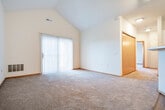 Located at 9244 Waterside St in Madison, Wisconsin, this two-story, one-bedroom, two-bathroom home offers a thoughtfully arranged layout spread across two floors. The main level features a open-concept living area with plush carpeting, a sliding glass door that invites natural light, and track lighting overhead. The kitchen is well-equipped with warm wood cabinetry, white appliances including a range, microwave, and refrigerator, a double-basin sink, and a peninsula countertop that provides additional workspace and a natural division from the living area. Wood-look plank flooring runs through the kitchen and entry areas, complementing the warm wood trim throughout. A convenient in-unit laundry area houses a full-size washer and dryer. The upper level hosts the spacious primary bedroom, featuring vaulted ceilings with a ceiling fan, a large window that fills the room with natural light and outdoor views, and plush carpeting. A generously sized walk-in closet with built-in shelving and hanging rods provides ample storage. Both bathrooms are well-appointed, with one featuring a glass-door shower stall, wood-framed vanity, and open shelving. The home's two-story design, vaulted ceilings, and abundant storage make it a highly functional and comfortable residence.