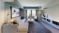 This 2-bedroom, 2-bathroom residence combines contemporary design with functional living across a well-organized single-floor layout. The living room serves as the heart of the home, featuring a soothing palette of sage green and neutral tones, large windows that invite natural light, hardwood-style flooring, and ample space for a tufted sectional sofa, accent seating, and a low-profile media console. A large framed artwork anchors the room with artistic character.

The kitchen is outfitted with gray shaker-style cabinetry, white countertops, stainless steel appliances including a refrigerator, range, and over-the-range microwave, complemented by a light wood floor and classic tile backsplash.

The primary bedroom is a serene retreat with natural light streaming through green-trimmed windows, light hardwood flooring, and an organized walk-in closet. The second bedroom, accented in soft sage, features its own closet and views of lush greenery outside.

Both bathrooms are well-appointed: one offers a walk-in shower with a vanity and framed mirror, while the other includes a full soaking tub and shower combo with a bold dark accent wall. The residence also features an in-unit laundry area, completing its practical and polished appeal.