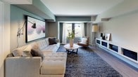 This 2-bedroom, 2-bathroom residence combines contemporary design with functional living across a well-organized single-floor layout. The living room serves as the heart of the home, featuring a soothing palette of sage green and neutral tones, large windows that invite natural light, hardwood-style flooring, and ample space for a tufted sectional sofa, accent seating, and a low-profile media console. A large framed artwork anchors the room with artistic character.

The kitchen is outfitted with gray shaker-style cabinetry, white countertops, stainless steel appliances including a refrigerator, range, and over-the-range microwave, complemented by a light wood floor and classic tile backsplash.

The primary bedroom is a serene retreat with natural light streaming through green-trimmed windows, light hardwood flooring, and an organized walk-in closet. The second bedroom, accented in soft sage, features its own closet and views of lush greenery outside.

Both bathrooms are well-appointed: one offers a walk-in shower with a vanity and framed mirror, while the other includes a full soaking tub and shower combo with a bold dark accent wall. The residence also features an in-unit laundry area, completing its practical and polished appeal.