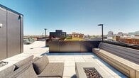 Located at 1314 Spring Garden St in Philadelphia's vibrant Spring Garden neighborhood, this rooftop terrace offers a well-appointed outdoor amenity space with commanding views of the surrounding cityscape. The terrace is finished with large-format porcelain pavers throughout, creating a clean, contemporary aesthetic underfoot.

Multiple distinct seating zones are thoughtfully arranged across the rooftop, each offering a unique vantage point of the Philadelphia skyline. Modular lounge furniture in neutral tones provides ample seating for gathering and relaxation. Built-in wood-clad bench seating adds a warm, refined contrast to the modern material palette, while centrally positioned fire pit tables serve as focal anchors for intimate conversation areas.

A raised planter bed introduces a touch of greenery to the rooftop, softening the urban environment. Sleek pole-mounted lighting fixtures are positioned throughout the space, ensuring functionality well into the evening hours. Utility access panels and storage elements are neatly integrated into the design without disrupting the overall aesthetic.

Surrounded by a combination of glass railings and wood-paneled parapet walls, the terrace maintains an open, airy feel while framing iconic Philadelphia architecture and the broader city skyline. This rooftop space is ideally suited for both casual lounging and social gatherings in the heart of Philadelphia.