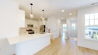 Located at 50 Kirby Ave in Somerville, NJ, this thoughtfully designed 4-bedroom, 3-bathroom home offers a bright and modern living experience across a well-utilized single floor. The open-concept kitchen and living area serves as the heart of the home, featuring crisp white shaker cabinetry with matte black hardware, a white quartz peninsula, classic subway tile backsplash, stainless steel appliances, and stylish glass pendant lighting. Light hardwood flooring flows seamlessly throughout, complementing the clean white walls and recessed lighting. The spacious living area is filled with natural light from large windows and sliding glass doors that open to an outdoor balcony. Each of the four bedrooms is generously sized, with large windows offering pleasant outdoor views and ceiling fans for added comfort. The primary bedroom provides a notably expansive retreat. The three bathrooms are elegantly appointed with floating dark-toned vanities, white quartz countertops, framed mirrors, and modern fixtures. The primary bath features a double-sink vanity and a frameless glass-enclosed walk-in shower. Carpeted stairs lead to additional levels, completing this well-appointed, move-in-ready home.