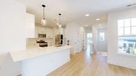 Located at 50 Kirby Ave in Somerville, NJ, this thoughtfully designed 4-bedroom, 3-bathroom home offers a bright and modern living experience across a well-utilized single floor. The open-concept kitchen and living area serves as the heart of the home, featuring crisp white shaker cabinetry with matte black hardware, a white quartz peninsula, classic subway tile backsplash, stainless steel appliances, and stylish glass pendant lighting. Light hardwood flooring flows seamlessly throughout, complementing the clean white walls and recessed lighting. The spacious living area is filled with natural light from large windows and sliding glass doors that open to an outdoor balcony. Each of the four bedrooms is generously sized, with large windows offering pleasant outdoor views and ceiling fans for added comfort. The primary bedroom provides a notably expansive retreat. The three bathrooms are elegantly appointed with floating dark-toned vanities, white quartz countertops, framed mirrors, and modern fixtures. The primary bath features a double-sink vanity and a frameless glass-enclosed walk-in shower. Carpeted stairs lead to additional levels, completing this well-appointed, move-in-ready home.