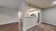This single-floor, 2-bedroom, 1-bathroom residence offers a thoughtfully organized layout that maximizes functionality across its comfortably sized footprint. The open living and dining area is anchored by rich, dark hardwood-style flooring that flows throughout the main living spaces, creating a warm and cohesive aesthetic. A large window at one end of the living area invites natural light, enhancing the sense of openness.

The kitchen is a standout feature, boasting white shaker-style cabinetry, granite countertops, a slate-tile backsplash, and a full suite of stainless steel appliances including a refrigerator and gas range. A pass-through counter connects the kitchen to the living area, promoting an open and social atmosphere.

Both bedrooms are carpeted for comfort and include windows that provide natural light and outdoor views. The primary bedroom is a well-proportioned retreat, while the second bedroom also benefits from dual windows. Each bedroom is served by closet space with built-in wire shelving.

The bathroom features a full tub-shower combination with clean white surrounds and hardwood-style flooring. A dedicated laundry room with washer/dryer hookups and wire shelving adds practical convenience. A central hallway connects all rooms, completing this efficiently designed and move-in-ready home.