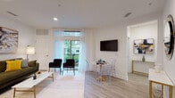 This well-appointed single-floor residence at 59 2nd Ave in Raritan, New Jersey, offers a thoughtfully designed open-concept layout with modern finishes throughout. The living and dining area is bright and airy, featuring light hardwood-style flooring, recessed lighting, and sheer white curtains that frame large windows and a sliding glass door leading to a private balcony with lush outdoor views. A wall-mounted flat-screen TV anchors the living space, while a round marble-top dining table with contemporary acrylic chairs adds a refined, stylish touch. The kitchen is equipped with dark espresso cabinetry, white quartz countertops, stainless steel appliances including a gas range, built-in microwave, and dishwasher, along with a deep undermount sink. The bedroom offers a serene retreat with a large window overlooking greenery, hardwood-style floors, and warm ambient lighting. A dedicated home office nook features built-in leaning shelves and a compact desk, ideal for remote work or study. The unit also includes a practical utility area with a stacked Bosch washer and dryer, a dedicated water heater closet, and ample storage. Clean white walls and consistent flooring throughout create a cohesive, modern aesthetic.