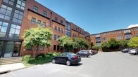 Located at 360, this space occupies one floor within a well-maintained multi-story building that blends classic and contemporary architectural elements. The building's exterior showcases traditional red brick construction accented by dark-framed windows, offering a professional and polished aesthetic. Large glass panel sections add a modern touch, allowing natural light to filter through the facade.

The building is set within a landscaped environment, with mature trees and well-kept shrubbery lining the perimeter, contributing to a welcoming and pleasant atmosphere. A paved parking area with dedicated spaces sits directly in front of the building, providing convenient on-site access for occupants and visitors alike.

The overall character of the building suggests a commercial or mixed-use environment, well-suited for professional or office use. The combination of brick detailing, contemporary glazing, and greenery creates a balanced, inviting appearance. The surrounding grounds are neat and orderly, enhancing the professional ambiance of the location and making it an appealing setting for those who work or visit within.