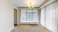 Located at 12500 Edgewater Dr in Lakewood, Ohio, this single-floor residence offers a thoughtfully designed layout with a clean, neutral aesthetic throughout. The living area is a standout space, featuring large floor-to-ceiling windows fitted with vertical blinds that allow generous natural light to fill the room. A decorative chandelier adds a touch of elegance, while plush carpeting provides warmth underfoot. An adjacent room, also carpeted and brightened by expansive windows, includes a ceiling fan and closet, making it well-suited as a bedroom. A separate carpeted room with its own window and closet offers additional flexibility as a second bedroom or den. The kitchen is functional and well-equipped, featuring white cabinetry, granite-toned countertops, light hardwood-style flooring, and a full suite of appliances including a refrigerator, electric range, microwave, and dishwasher. The layout connects efficiently to the main living areas via a hardwood-floored entryway corridor. Two bathrooms serve the residence — one featuring a tub-shower combination with white tile surround, and the other a half-bath configuration — both finished with white vanity cabinetry, mirrored medicine cabinets, and hardwood-style flooring. The overall ambiance is bright, neutral, and move-in ready.