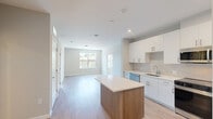 This well-appointed 2-bedroom, 1-bathroom unit at 303 Lincoln Street in Marlborough, Massachusetts offers a thoughtfully designed, single-floor layout with modern finishes throughout. Light wood-tone flooring flows continuously across the entire living space, creating a cohesive and airy aesthetic.

The open-concept kitchen is a standout feature, outfitted with crisp white cabinetry, a subtle tile backsplash, white quartz countertops, and a full suite of stainless steel appliances including a range, microwave, dishwasher, and refrigerator. A kitchen island with warm wood-tone base adds both workspace and visual contrast.

The open living area adjoins the kitchen seamlessly, offering a flexible and functional arrangement. Both bedrooms are comfortably sized and share consistent neutral-toned walls and light flooring. Large windows in each bedroom invite abundant natural light and provide views of the surrounding Marlborough neighborhood.

The bathroom is finished in a clean, contemporary style with a glass-enclosed walk-in shower, wood-tone vanity with white countertop, and a mirrored medicine cabinet. A dedicated closet provides practical storage. The overall ambiance is bright, clean, and move-in ready, reflecting a modern residential design sensibility throughout.