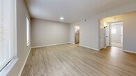 Located at 400 Cox Landing in Newport News, Virginia, this single-floor residence offers a thoughtfully updated interior with a clean, modern aesthetic. Light neutral tones and white trim carry throughout the home, creating a cohesive and welcoming atmosphere.

The open living area is bright and airy, featuring light wood-look luxury vinyl plank flooring and multiple windows that invite natural light. The space flows seamlessly toward the kitchen, which stands out as a key feature of the home. The kitchen is equipped with white cabinetry accented by matte black hardware, granite-look countertops, a stainless steel range and dishwasher, and a stainless refrigerator — all contributing to a polished, functional workspace.

The bedroom offers a comfortable retreat with plush wall-to-wall carpeting, neutral walls, and a window with blinds providing natural light and privacy. A closet with louvered doors provides convenient storage.

The bathroom continues the home's modern design language with white cabinetry, a framed mirror, a white countertop vanity, and matte black fixture accents. The floor plan, as seen in the 3D overview, reveals a well-organized single-level layout that maximizes the use of space across living, sleeping, cooking, and bathing areas.