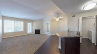 This single-floor residence offers a thoughtfully designed open-concept layout that seamlessly connects the living, dining, and kitchen areas. The living room is a welcoming space anchored by a classic fireplace with a white mantel, complemented by neutral-toned carpet and a pendant light fixture overhead. Natural light filters in through blinds-covered windows, adding warmth to the space.

The kitchen is outfitted with dark espresso cabinetry, granite-style countertops, and stainless steel appliances, including a refrigerator, electric range, and over-the-range microwave. A raised breakfast bar peninsula serves as a functional divider between the kitchen and living areas. Dark hardwood-style flooring runs throughout the kitchen and dining zone, creating a clean contrast with the carpeted living spaces.

The bedrooms are generously sized, featuring plush carpet, vaulted or standard ceilings depending on the room, and ample natural light from large windows with exterior views. The primary bedroom includes access to a walk-in closet area. The bathroom features a full soaking tub with tiled surround, dark vanity cabinetry with granite-style countertops, and hardwood-style flooring. A dedicated in-unit laundry area adds everyday convenience.