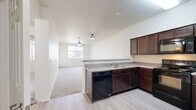 Located at 100 Penzance Ave in Chico, CA, this well-appointed two-bedroom, two-bathroom residence offers a practical and comfortable single-floor layout. The open-concept kitchen and living area serves as the heart of the home, where rich dark wood cabinetry, light countertops, and black appliances — including a dishwasher, range, and refrigerator — combine for a functional cooking space. A peninsula counter separates the kitchen from the carpeted living room, which features a ceiling fan and a window that brings in natural light. A hallway leads from the kitchen to the rest of the home, lined with closets and providing easy access to both bedrooms and bathrooms. The primary bedroom is generously sized, featuring plush carpet, a ceiling fan, and windows that offer views of the surrounding landscape. The second bedroom mirrors this comfortable layout with its own window and ceiling fan. Both bathrooms are clean and functional, with one featuring a tub-shower combination with tiled surround and wood-look vinyl flooring. Two closets provide ample storage throughout. The light-toned walls and neutral finishes throughout the home create a bright, cohesive aesthetic well-suited to a variety of living arrangements.