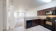 Located at 100 Penzance Ave in Chico, CA, this well-appointed two-bedroom, two-bathroom residence offers a practical and comfortable single-floor layout. The open-concept kitchen and living area serves as the heart of the home, where rich dark wood cabinetry, light countertops, and black appliances — including a dishwasher, range, and refrigerator — combine for a functional cooking space. A peninsula counter separates the kitchen from the carpeted living room, which features a ceiling fan and a window that brings in natural light. A hallway leads from the kitchen to the rest of the home, lined with closets and providing easy access to both bedrooms and bathrooms. The primary bedroom is generously sized, featuring plush carpet, a ceiling fan, and windows that offer views of the surrounding landscape. The second bedroom mirrors this comfortable layout with its own window and ceiling fan. Both bathrooms are clean and functional, with one featuring a tub-shower combination with tiled surround and wood-look vinyl flooring. Two closets provide ample storage throughout. The light-toned walls and neutral finishes throughout the home create a bright, cohesive aesthetic well-suited to a variety of living arrangements.