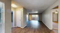 This thoughtfully designed 2-bedroom, 2-bathroom single-story residence offers a comfortable and functional layout across a generous footprint. The living areas feature rich dark hardwood-style flooring that flows throughout, complemented by neutral-toned walls and textured ceilings that lend a classic character to the space. A standout feature of the main living area is the striking white wood-paneled fireplace with a diagonal shiplap surround, serving as an eye-catching focal point. Sliding glass doors lead to a private balcony, allowing natural light to fill the room and offering a seamless indoor-outdoor connection. The galley-style kitchen is well-equipped with white cabinetry, light quartz-style countertops, a subway tile backsplash, and black appliances including a refrigerator, range, and microwave. Both bedrooms are carpeted and feature ceiling fans with light fixtures, offering a comfortable retreat. The spacious primary bedroom includes its own closet. Each bathroom is finished with white vanity cabinetry, light countertops, and framed mirrors. Additional conveniences include dedicated closets, hallways connecting the living spaces, and an in-unit laundry area, making this a complete and practical home.