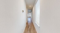 This two-story home offers a well-organized layout across two floors, providing ample space for comfortable living. The main level hosts the combined kitchen and living area, two hallways, and multiple bathrooms, while the upper floor accommodates the majority of the bedrooms and additional bathrooms. Throughout the home, light-toned wood-look flooring creates a cohesive, clean aesthetic that complements the crisp white walls and modern finishes.

The kitchen is a functional highlight, featuring light natural wood cabinetry, granite-look countertops, stainless steel appliances including a French door refrigerator and microwave, and generous counter space. The open layout connects seamlessly to the living area, making it ideal for everyday use and entertaining.

The five bedrooms are bright and well-proportioned, each finished with the same consistent wood-look flooring and neutral white walls. The primary bedroom offers a comfortable footprint with a dedicated closet equipped with a full-width hanging rod and shelving. The four bathrooms are cleanly designed, with at least one featuring a tiled tub-shower combination with a built-in shelf niche.

A dedicated laundry room comes equipped with a full-size washer and dryer and overhead shelving for added storage. Natural light filters throughout the home via windows fitted with white horizontal blinds, contributing to the bright and airy ambiance that defines this well-appointed residence.