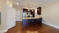 Located on Matrix Way in Hudson, Massachusetts, this single-floor residence offers a thoughtfully designed open-concept layout with a seamless blend of style and functionality. The kitchen is a standout feature, showcasing rich dark-wood cabinetry that reaches toward the ceiling, polished granite countertops with warm tonal variation, and a full suite of stainless steel appliances including a French door refrigerator, electric range, and built-in microwave. A curved peninsula with an undermount sink and pendant lighting above adds both visual interest and practical workspace, while recessed lighting and crown molding lend a refined finish overhead. Gleaming hardwood floors flow throughout the main living and kitchen areas, anchoring the open feel of the space. The living area benefits from large windows that frame views of the surrounding greenery, flooding the interior with natural light. Bedrooms are carpeted for comfort, each featuring neutral tones and generous closet space, with at least one walk-in closet equipped with built-in shelving. The bathroom is finished with large-format tile flooring, a dark-cabinet vanity topped with granite, an oversized mirror, and a glass-enclosed walk-in shower, delivering a clean and polished aesthetic throughout.