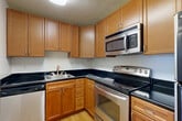 Located at 4849 Connecticut Ave NW in Washington, DC, Unit 604 is a well-appointed 2-bedroom, 2-bathroom residence offering a thoughtfully designed single-level floor plan. The open living and dining areas are anchored by warm hardwood flooring and neutral-toned walls, with natural light flowing in through large sliding glass doors that lead to a private balcony overlooking lush greenery. The kitchen is efficiently laid out with warm honey-toned cabinetry, dark granite countertops, and a full suite of stainless steel appliances including an electric range, built-in microwave, dishwasher, and refrigerator — all set atop light hardwood floors. Both bedrooms are comfortably sized and feature plush carpeting and dedicated closets, with the primary bedroom offering generous proportions. The two bathrooms are finished with neutral tile surrounds, full soaking tubs with showers, and white cabinetry for storage. A hallway with additional closets provides practical storage throughout. With four closets total and two combined living and dining areas, this residence balances comfort and functionality in one of Washington, DC's established Northwest neighborhoods.
