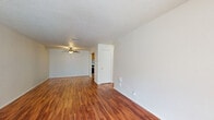 This 690 square foot apartment, located in Summit West - 3E - A1, offers a thoughtful one-bedroom, one-bathroom layout. The space is characterized by a blend of warm wood flooring in the main living areas and plush carpeting in the bedroom, creating distinct zones within the home.

The kitchen is a standout feature, boasting oak cabinetry that provides ample storage. Stainless steel appliances, including a refrigerator and dishwasher, add a modern touch. The adjacent laundry area with a washer and dryer enhances convenience.

The living room is spacious and inviting, featuring a large window that floods the area with natural light. A ceiling fan adds both style and functionality. The bedroom, measuring 160 square feet, offers a cozy retreat with a built-in closet for storage.

Throughout the apartment, neutral-toned walls create a blank canvas for personalization. The bathroom, while not pictured, likely continues the apartment's blend of functionality and style.

This well-designed space maximizes every square foot, offering a comfortable and efficient living environment. The combination of practical amenities and thoughtful design elements makes this apartment an attractive option for those seeking a compact yet well-appointed home.