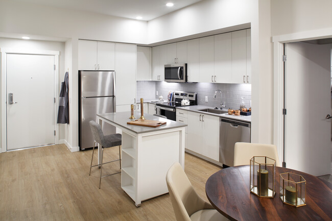 Phase II - Scheme C Kitchen with white cabinetry, grey tile backsplash, and stainless steel appliances - Avalon Newcastle Commons