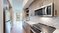 This well-appointed one-bedroom, one-bathroom unit offers a thoughtfully designed single-floor layout encompassing a comfortable living area, dining space, fully equipped kitchen, two closets, and a full bathroom. The galley-style kitchen is a standout feature, showcasing two-tone wood cabinetry with matte black hardware, crisp white quartz countertops, a herringbone-pattern tile backsplash, and a full suite of stainless steel Whirlpool appliances including a range, built-in microwave, dishwasher, and refrigerator. Warm hardwood-style flooring runs throughout the unit, lending a cohesive and modern aesthetic. The living area is bright and open, benefiting from large windows that frame lush, green tree views and allow natural light to fill the space. The bedroom is a comfortable size, featuring tall ceilings, multiple windows with outdoor views, and direct access to a private outdoor balcony area. The bathroom is clean and functional, offering a vanity with wood cabinetry and white countertop, a full tub and shower combination with white tile surround, and coordinating hardwood-style flooring. Two dedicated closets provide ample storage throughout the unit. The overall design is clean, contemporary, and move-in ready.