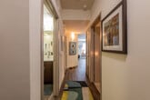This single-story residence offers a thoughtfully designed layout connecting living, sleeping, dining, and utility spaces in a cohesive flow. The entryway hallway features built-in white shelving for storage and is accented by framed wall art, setting a clean, modern tone. Wood-look flooring extends through the main living and kitchen areas, adding warmth and continuity.

The kitchen is a standout feature, equipped with dark espresso cabinetry, white countertops, stainless steel appliances including a refrigerator, dishwasher, range, and microwave, along with a classic subway tile backsplash. A wooden dining table positioned nearby creates a natural eat-in area.

The living room benefits from multiple windows fitted with horizontal blinds, allowing generous natural light and views of surrounding greenery. Bedrooms are carpeted and well-proportioned, with windows providing additional outdoor views. One bedroom notably features vaulted-style ceilings that enhance the sense of space.

Bathrooms include tub-shower combinations, wood-look vinyl flooring, dark vanity cabinetry, and open built-in shelving. One bathroom provides direct access to a well-organized walk-in closet with multiple shelving tiers, adding practical storage throughout the residence.