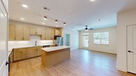 Located at 15576 Voyage Pl in Waldorf, MD, this single-floor home offers four bedrooms and two bathrooms across a well-organized layout. Light wood-style flooring runs throughout the living areas and bedrooms, creating a cohesive and contemporary aesthetic. The open-concept living area features a ceiling fan with built-in lighting and multiple windows that invite abundant natural light, giving the space an airy, welcoming feel. The kitchen is a standout feature, equipped with a center island topped with white quartz-style countertops, light wood shaker cabinetry with matte black hardware, a full suite of stainless steel appliances including a refrigerator, range, over-the-range microwave, and dishwasher, plus a clean subway tile backsplash. The primary bedroom offers a comfortable footprint with its own walk-in closet outfitted with wire shelving on both walls, providing excellent storage capacity. Additional bedrooms are well-proportioned, each featuring ceiling fans with windows for natural light. The bathrooms are finished with large-format tile surrounds around the soaking tub and clean, neutral fixtures. The home's neutral palette of whites and warm beiges throughout creates a bright, move-in ready environment.